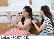 Asian young women conducting their weekly holiday routines from getting up, putting on cosmetics and relaxing. Стоковое фото, агентство Ingram Publishing / Фотобанк Лори