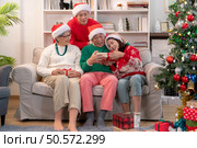 Family members are exchanging gifts with each other during the Christmas holiday at home. Стоковое фото, агентство Ingram Publishing / Фотобанк Лори