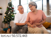 Grandfather and grandmother are giving each other a relaxing massage while waiting to meet their children and grandchildren, who will join them for a meal during the Christmas holiday at home. Стоковое фото, агентство Ingram Publishing / Фотобанк Лори