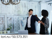 In a modern clothes fashion room, a clothing designer or tailor allows buyers to try on molded outfits before sewing them. Стоковое фото, агентство Ingram Publishing / Фотобанк Лори