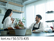 A husband wears an apron while cooking dinner with his wife. The duo took a break to sip coffee and sample the completed bread. Стоковое фото, агентство Ingram Publishing / Фотобанк Лори