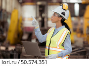 Portrait of railway technician worker in safety vest and helmet working with blueprint at train repair station. Стоковое фото, агентство Ingram Publishing / Фотобанк Лори