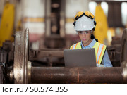 Railway technician in uniform and helmet inspect the train wheels removed from the locomotives in the train workshop. Стоковое фото, агентство Ingram Publishing / Фотобанк Лори