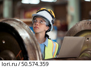 Railway technician in uniform and helmet inspect the train wheels removed from the locomotives in the train workshop. Стоковое фото, агентство Ingram Publishing / Фотобанк Лори