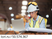 Portrait of railway technician worker in safety vest and helmet working with blueprint at train repair station. Стоковое фото, агентство Ingram Publishing / Фотобанк Лори