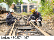 Railway technicians and engineers, Working on the train tracks at train station. Стоковое фото, агентство Ingram Publishing / Фотобанк Лори