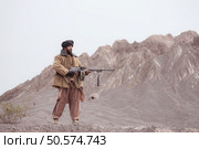 A Taliban soldier stands with a machine gun, In the desert mountain landscape. Стоковое фото, агентство Ingram Publishing / Фотобанк Лори