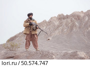 A Taliban soldier stands with a machine gun, In the desert mountain landscape. Стоковое фото, агентство Ingram Publishing / Фотобанк Лори