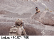 A Taliban soldier stands with a machine gun, Surrender to the allied soldiers, In the desert mountain terrain battlefield. Стоковое фото, агентство Ingram Publishing / Фотобанк Лори