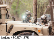 Soldiers in camouflage uniforms hold weapons ready to fire, By hiding on the side military communication vehicle. Стоковое фото, агентство Ingram Publishing / Фотобанк Лори