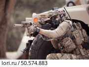 Soldiers in camouflage uniforms hold weapons ready to fire, By hiding on the side military communication vehicle. Стоковое фото, агентство Ingram Publishing / Фотобанк Лори