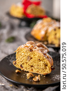 A generous slice of Bolo Rainha, a traditional Portuguese Christmas cake, is presented on a dark plate. Topped with almonds and powdered sugar, it showcases a rich, fruit-studded interior. Стоковое фото, агентство Ingram Publishing / Фотобанк Лори