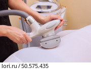 The masseur makes an hardware massage on the patient’s ass and legs in a white suit, close-up in a beauty salon. Стоковое фото, агентство Ingram Publishing / Фотобанк Лори