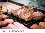 Delicious juicy rib eye steak on a barbecue grill BBQ is being flipped. Стоковое фото, агентство Ingram Publishing / Фотобанк Лори