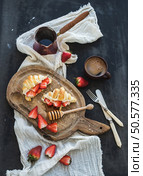 Breakfast set. Freshly baked croissants with strawberries, mascarpone, honey and coffee on rustic wooden board over dark grunge backdrop, top view. Breakfast set. Freshly baked croissants with strawberries, mascarpone, honey and coffee on rustic wooden board over dark grunge backdrop. Стоковое фото, агентство Ingram Publishing / Фотобанк Лори