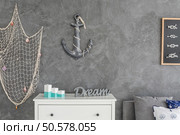 Modern ocean inspired  interior with white commode, fishing net and anchor hanging on the wall. Стоковое фото, агентство Ingram Publishing / Фотобанк Лори