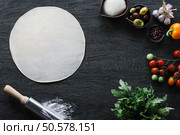 Italian pizza cooking process. Pizza dough and the ingredients: mozarella cheese, olives, pepper, garlic, tomato, rocket salad and spicies.. Italian pizza cooking. Стоковое фото, агентство Ingram Publishing / Фотобанк Лори