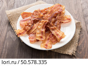 Closeup of fried bacon strips on white plate. Стоковое фото, агентство Ingram Publishing / Фотобанк Лори
