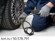Closeup Of Mechanic At Repair Service Station Checking Tyre Pressure With Gauge. Стоковое фото, агентство Ingram Publishing / Фотобанк Лори