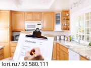 Closeup of a contractors clipboard as he write up an estimate for a kitchen remodel. Shallow depth of field with focus on clipboard. Стоковое фото, агентство Ingram Publishing / Фотобанк Лори