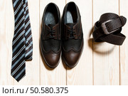 Collection of man’s accessories - new stylish bright footwear, tie and a belt on a dark wooden background. Стоковое фото, агентство Ingram Publishing / Фотобанк Лори