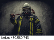 Portrait of firefighter in oxygen mask holding red rescue axe. Стоковое фото, агентство Ingram Publishing / Фотобанк Лори