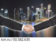 Two businessman shaking hands over blur night cityscape. Стоковое фото, агентство Ingram Publishing / Фотобанк Лори