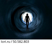 Woman is walking towards glaring light. it May symbolise escape, looking for exit or fredom and even death or clinical death . Psychodelic vision. Стоковое фото, агентство Ingram Publishing / Фотобанк Лори