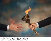 Businessman’s outstretched arm passing a flaming torch to another businessman’s open hand. Стоковое фото, агентство Ingram Publishing / Фотобанк Лори