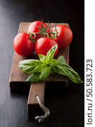 Fresh tomatoes and a sprig of basil on a wooden board. Стоковое фото, агентство Ingram Publishing / Фотобанк Лори
