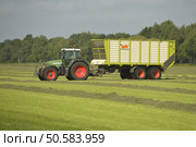 Agriculture, transport of cut grass with green tractor and grass trailer. Стоковое фото, агентство Ingram Publishing / Фотобанк Лори