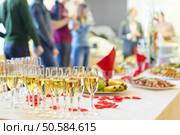 Banquet event. Table with the wineglasses, snacks and cocktails. People celebrating in the background.. Banquet event. Champagne on table. Стоковое фото, агентство Ingram Publishing / Фотобанк Лори