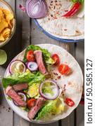 Overhead view on mexican style dinner with tacos, vegetables, nachos chips and guakomole, served over gray wooden table. Стоковое фото, агентство Ingram Publishing / Фотобанк Лори