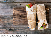 Mexican style dinner. Two papered tortillas burrito with beef and vegetables over old wooden background. Flat lay. With copy space. Tortillas and nachos. Стоковое фото, агентство Ingram Publishing / Фотобанк Лори