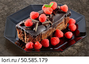 Chocolate cake with raspberries on black octagonal plate.. ChocCakeandRaspberries. Стоковое фото, агентство Ingram Publishing / Фотобанк Лори
