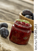 Closeup of a glass jar full of home made freshly cooked plum jam with two ripe plums next to it placed on a linen cloth. Стоковое фото, агентство Ingram Publishing / Фотобанк Лори