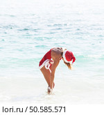 Beautiful woman in Mrs. Claus custume on tropical beach, Christmas vacations concept. Mrs. Claus on tropical beach. Стоковое фото, агентство Ingram Publishing / Фотобанк Лори