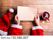 Santa Claus holding an empty wish list in his hands. Santa Claus and wishlist. Стоковое фото, агентство Ingram Publishing / Фотобанк Лори
