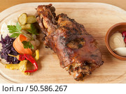 Roasted european pork knuckle on wood platter with vegetable garnish. Стоковое фото, агентство Ingram Publishing / Фотобанк Лори