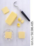 Butter on white wood table with slices, block, crystal butter dish and butter curler utensil. . Стоковое фото, агентство Ingram Publishing / Фотобанк Лори