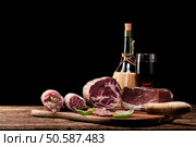 Parma ham pork salami, Italian production food  on wooden table over a balck background. Стоковое фото, агентство Ingram Publishing / Фотобанк Лори