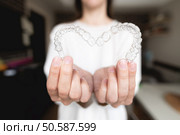 Dental care. Close-up of transparent aligners in the hands of a girl who is standing and showing a heart-shaped orthodontic device to the camera. selective focus.. Dental care. Close-up of transparent aligners in the hands of a girl who is standing and showing a heart-shaped orthodontic device to the camera. selective focus. Стоковое фото, агентство Ingram Publishing / Фотобанк Лори
