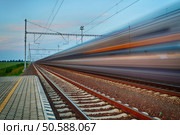 Railroad travel and transportation industry business concept: summer night view of high speed passenger train departing from railway station platform with motion blur effect. Стоковое фото, агентство Ingram Publishing / Фотобанк Лори