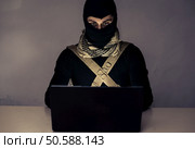 Terrorist working on his computer. Concept about international crisis, war and terrorism. Стоковое фото, агентство Ingram Publishing / Фотобанк Лори