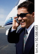 Businessman using cell phone next to airplane on tarmac. 24321109. Стоковое фото, агентство Ingram Publishing / Фотобанк Лори