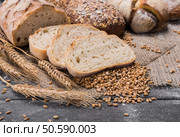 Plenty of sliced bread background. Bakery and grocery concept. Fresh, healthy sorts of rye and white loaves, sprinkled flour on sackcloth and rustic wood table, food closeup.. Bakery concept. Plenty of sliced bread background. Стоковое фото, агентство Ingram Publishing / Фотобанк Лори