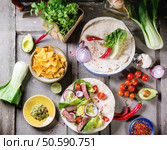 Overhead view on mexican style dinner with tacos, vegetables, nachos chips and guakomole, served over gray wooden table. Стоковое фото, агентство Ingram Publishing / Фотобанк Лори