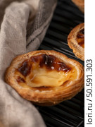 Golden-brown Portuguese custard tarts with flaky crusts, cooling on a wire rack. Стоковое фото, агентство Ingram Publishing / Фотобанк Лори