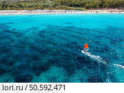 Aerial view of windsurfer on blue sea at sunny summer day. Windsurfing. Extreme sport and vacation. Top view of man on windsurfer board, waves, clear azure water in Sardinia, Italy. Tropical landscape. Стоковое фото, агентство Ingram Publishing / Фотобанк Лори