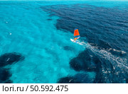 Aerial view of windsurfer on blue sea at sunny summer day. Windsurfing. Extreme sport and vacation. Top view of man on windsurfer board, waves, clear azure water in Sardinia, Italy. Tropical landscape. Стоковое фото, агентство Ingram Publishing / Фотобанк Лори